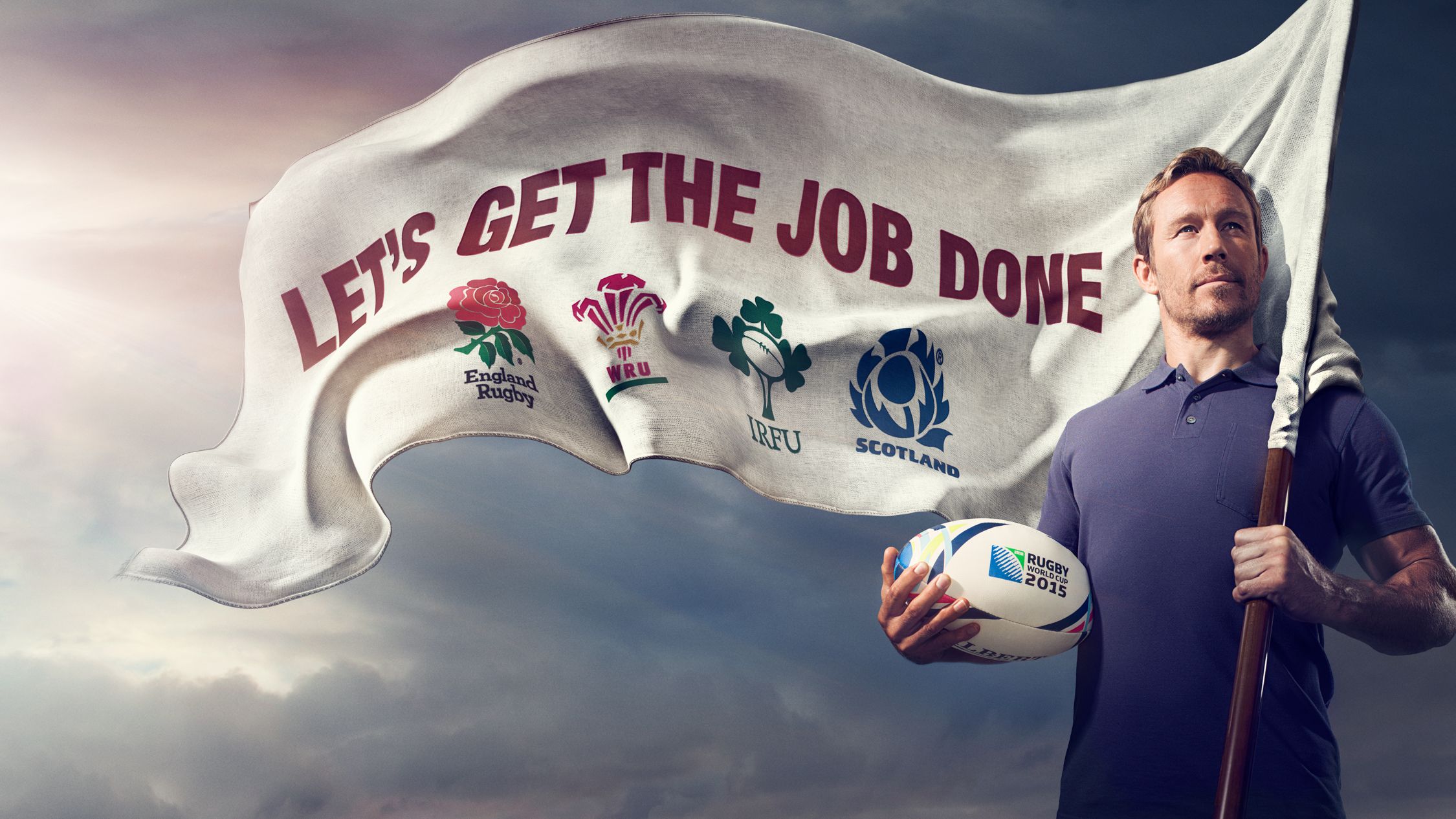 A man holding a rugby ball and a flag with a list of UK rugby teams, including England, Wales, Scotland, and Ireland, with a background of a cloudy sky.