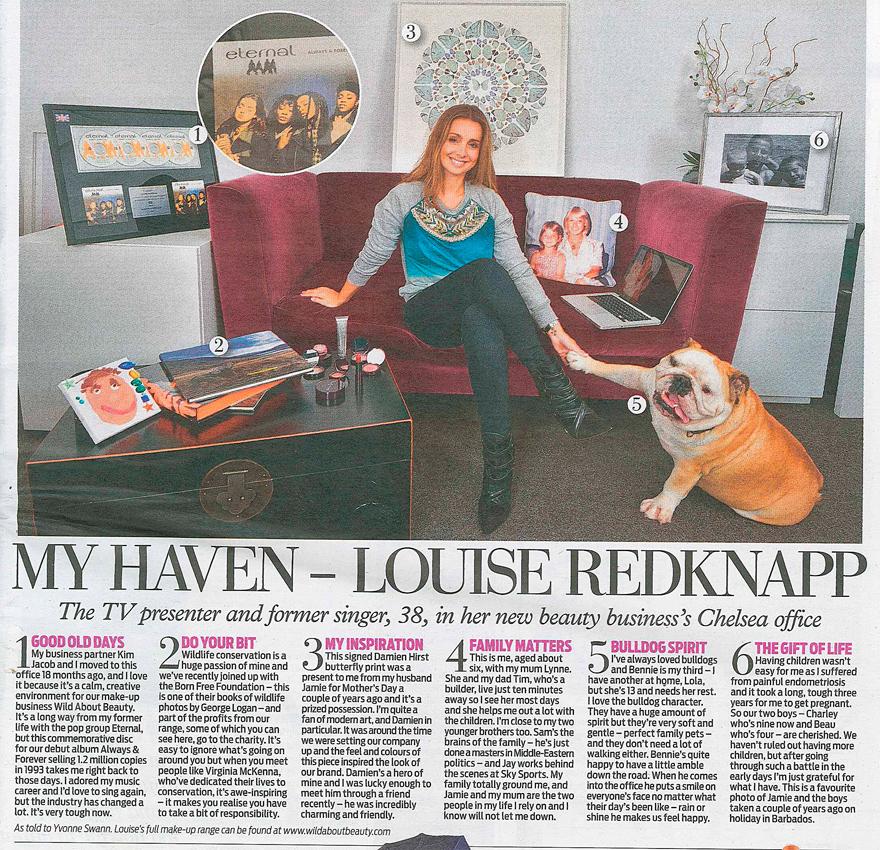 Woman sitting on a couch with a dog, surrounded by books, a laptop, and photographs on the wall.