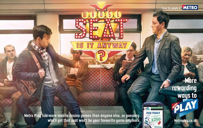 A man in a suit and tie is standing on a train, looking at a Metro Play mobile game on his phone.