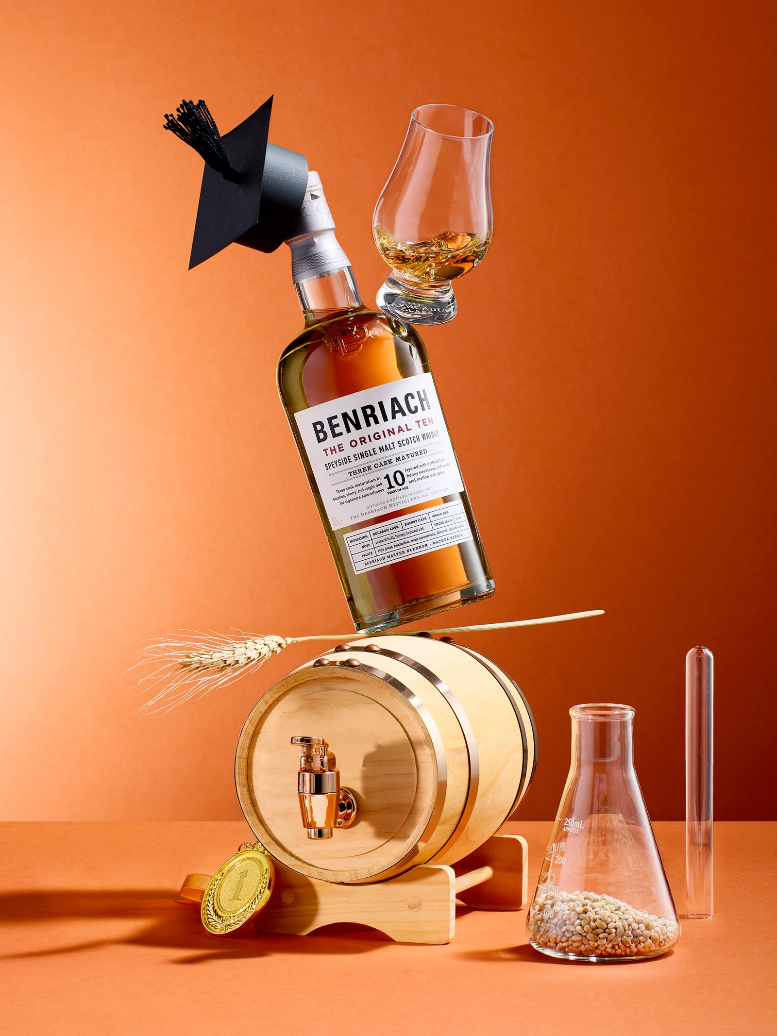 A bottle of whiskey, a glass, and a wooden barrel are suspended in mid-air, surrounded by various objects and props.