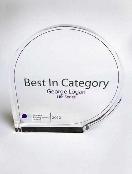 A glass award with a silver medal and a black, rectangular base.