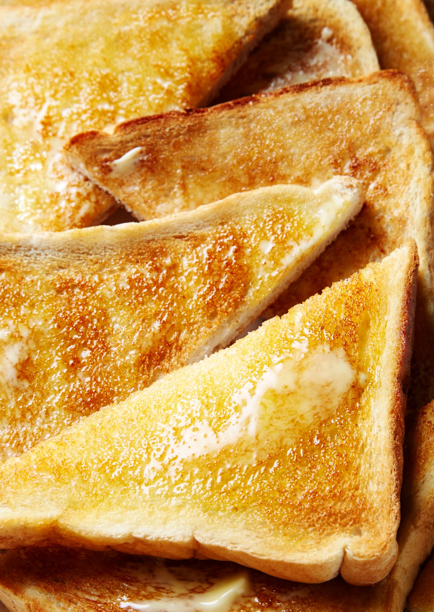 A stack of toasted bread slices, likely from a bakery or a breakfast meal, with a golden brown color and a crispy texture.