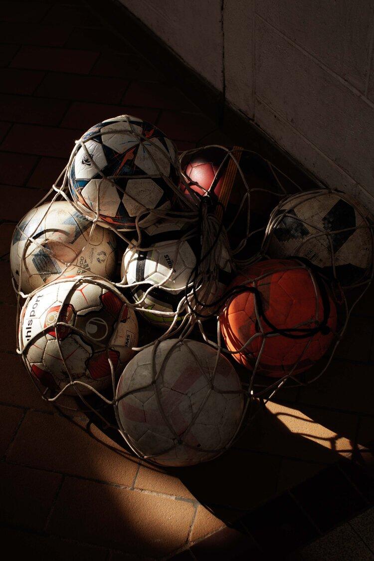 A collection of soccer balls in a net, likely used for training or storage.