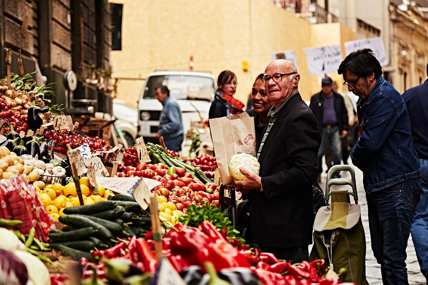 A bustling street market scene with fresh produce in a historic Italian city.