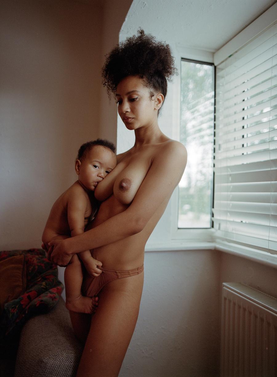 A woman holds a baby in a living room.