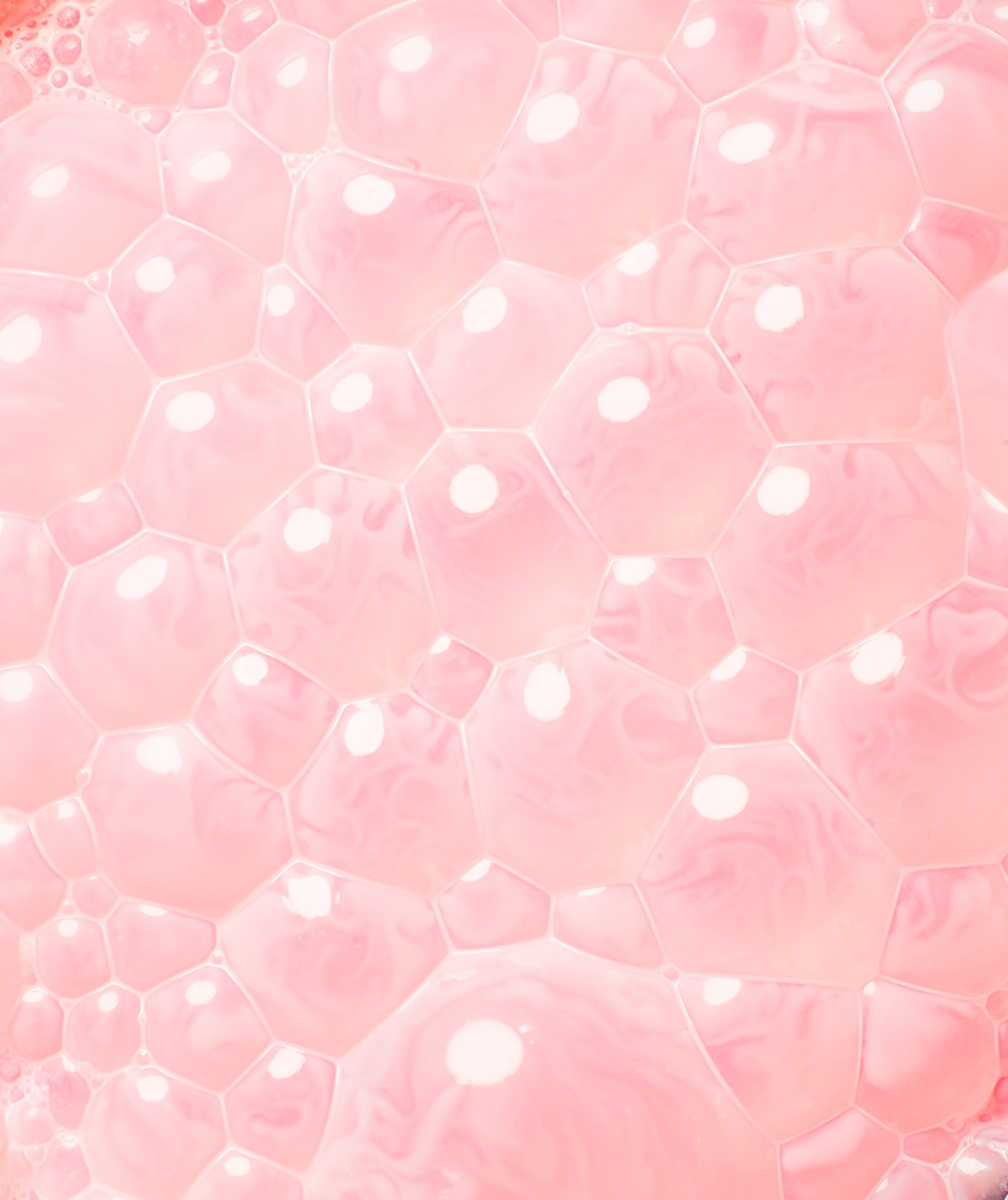 A close-up of a pink, soap-bubble-like, hexagonal patterned surface.