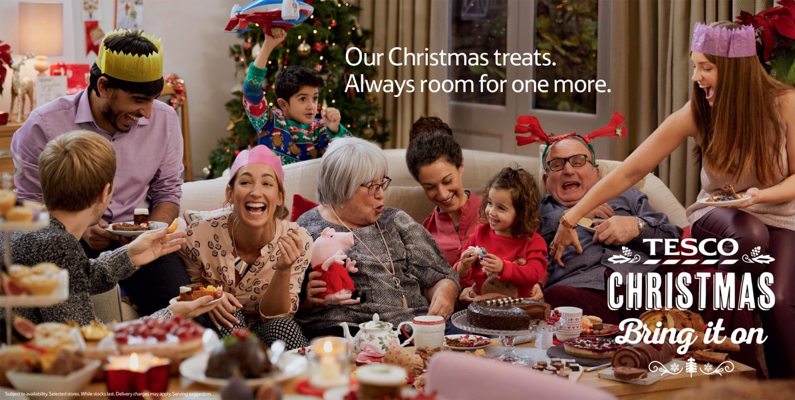 A group of people of all ages, including children, are gathered around a table laden with an assortment of sweet and savory foods, enjoying a festive holiday meal together.