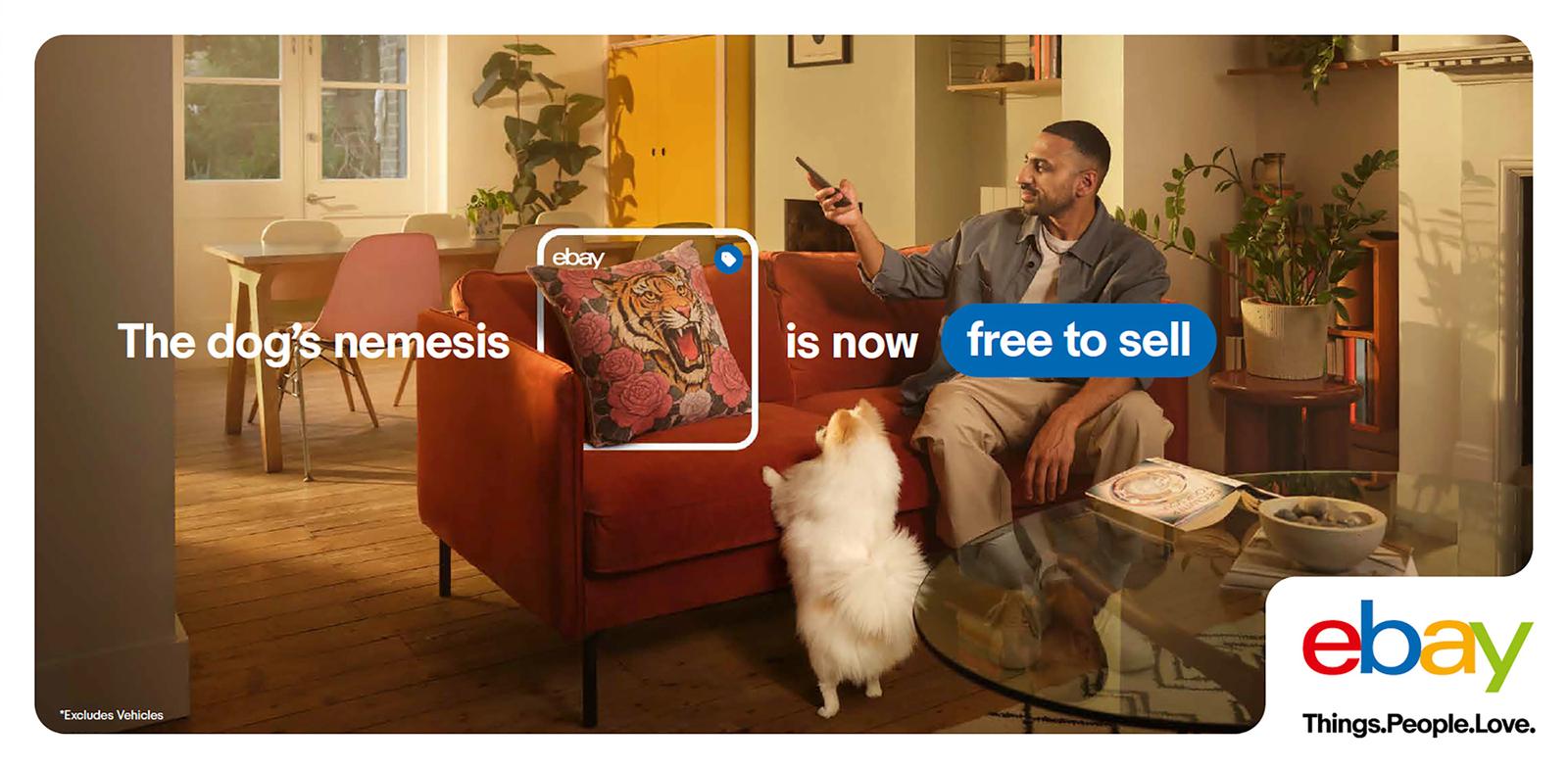A living room with a couch, a coffee table, and a man sitting on the couch with a phone in his hand, a dog sitting next to him.