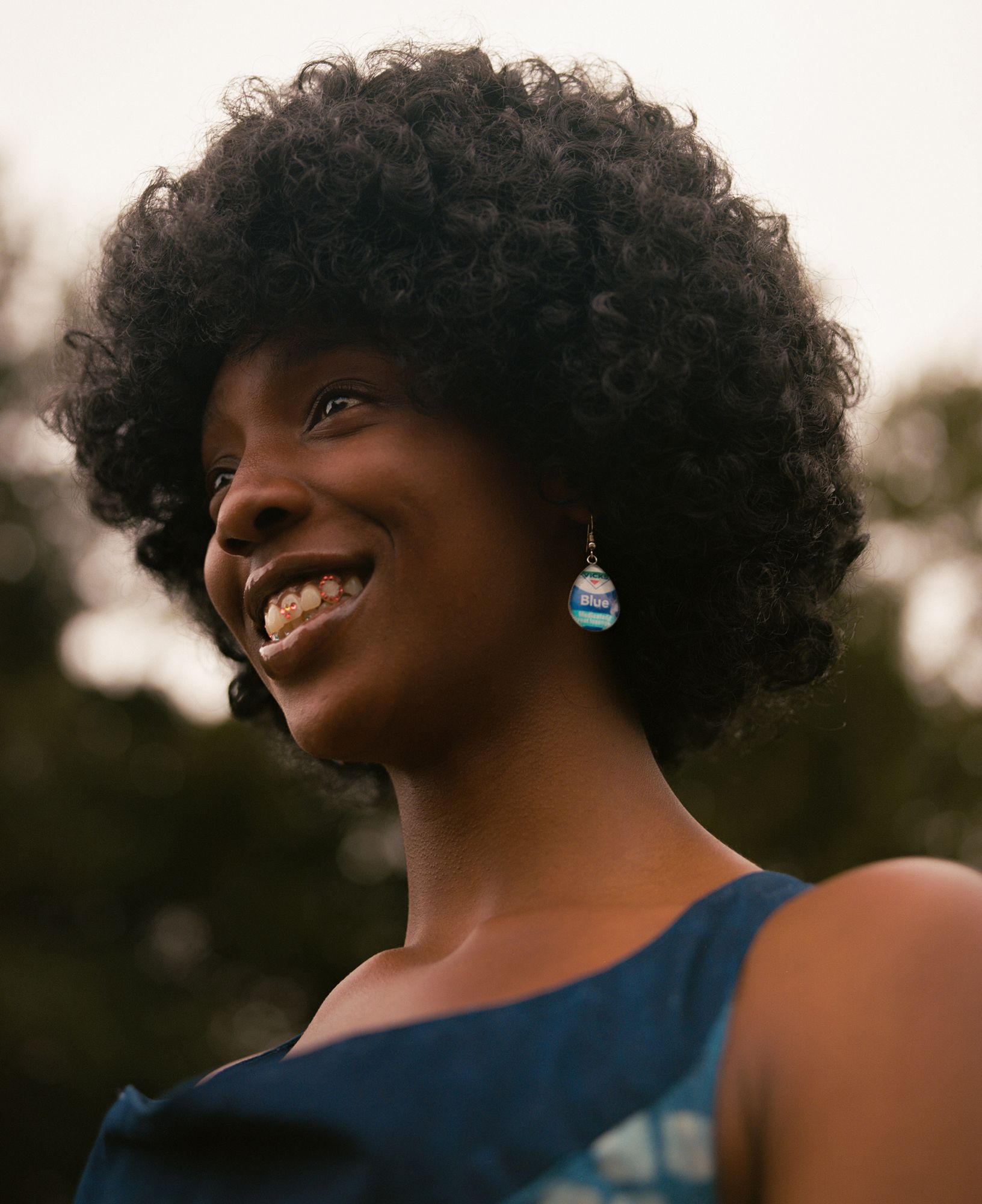 A woman wearing a blue dress with curly dark hair.