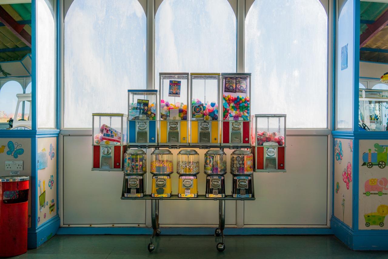 A room featuring a wall of gumball machines and a wall of windows.