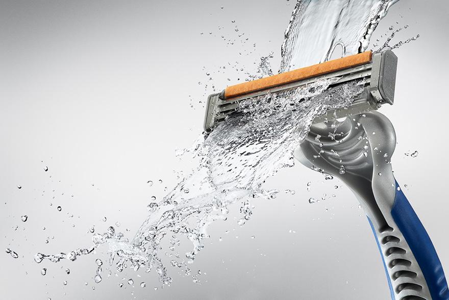 A razor with a splash of water, possibly in a bathroom or shower setting.
