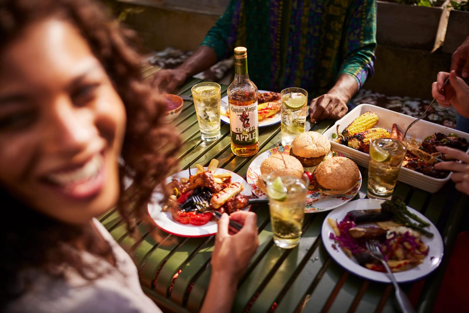 A group of people are enjoying a meal together at a table, with plates of food and glasses of drinks in front of them. The atmosphere appears to be casual and social, with the.
