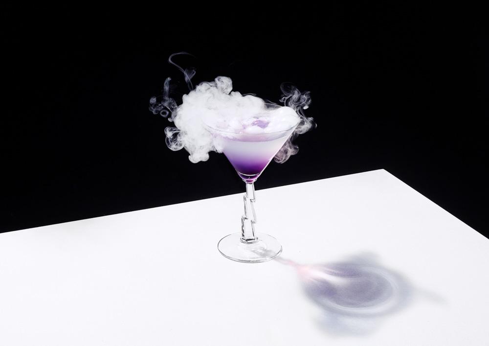 A cocktail in a glass with a smoke effect, surrounded by a cloud of fog.
