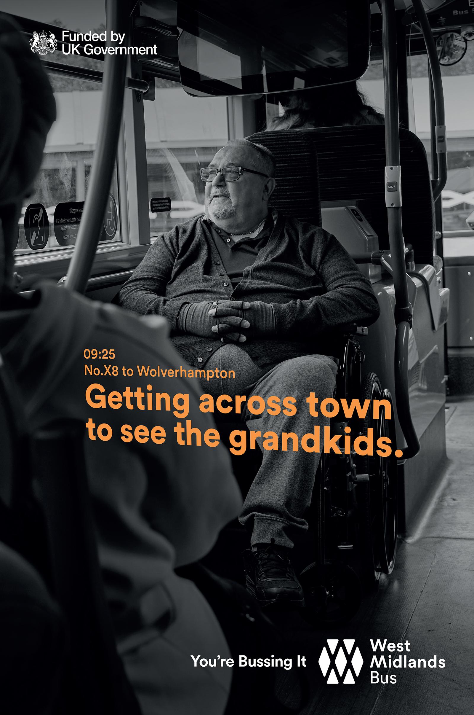 A man in a wheelchair is sitting on a bus, looking out the window at a city street.
