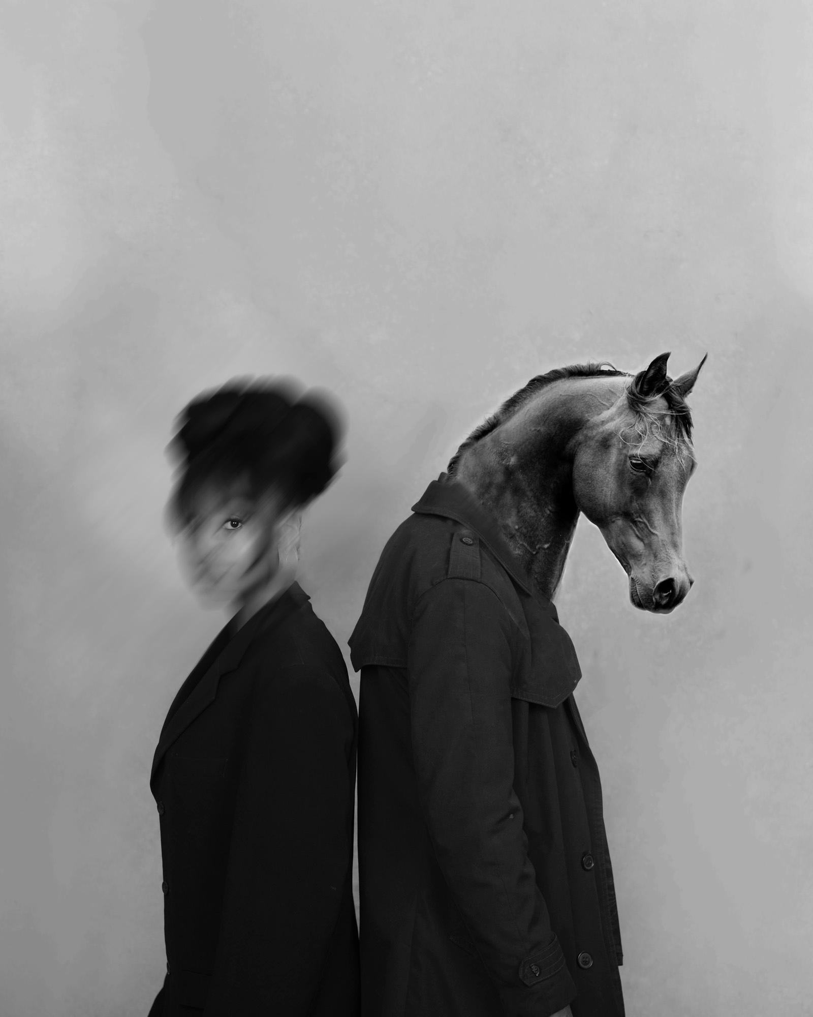 A person in a horse costume, wearing a black coat and standing in front of a plain background.