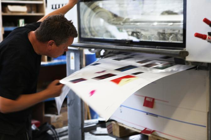 A man in a black t-shirt is examining a large print of a book in a studio.