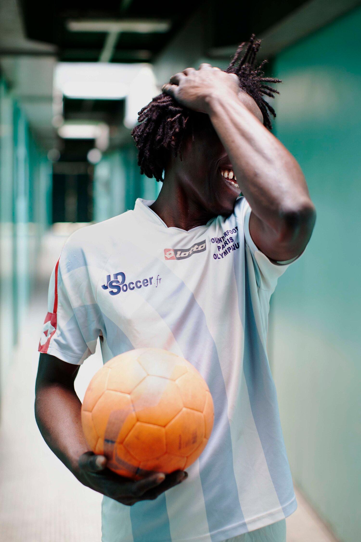 A person with dreadlocks and a football jersey holding a football.