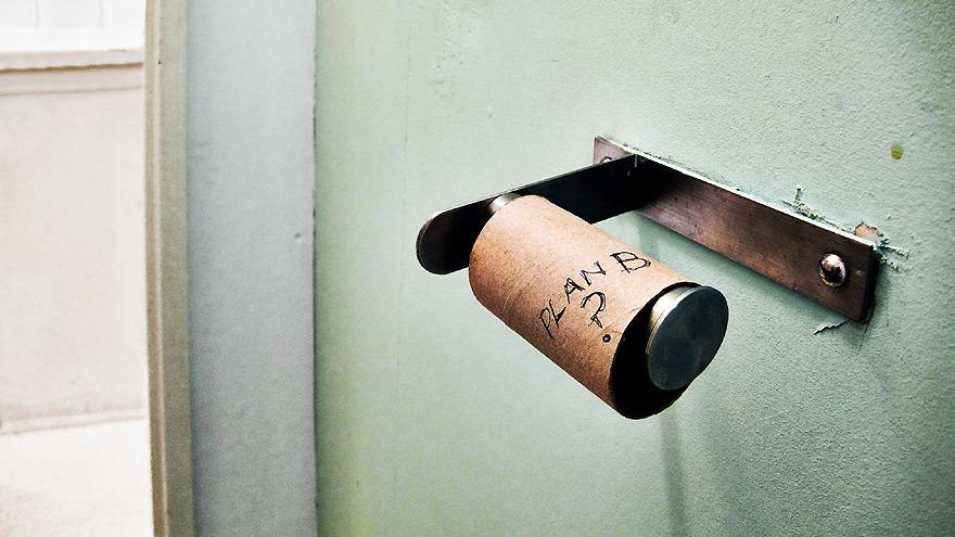 A roll of toilet paper on a wall, with a 'PLAN' label on it, suggesting a humorous or ironic message about planning or preparation.