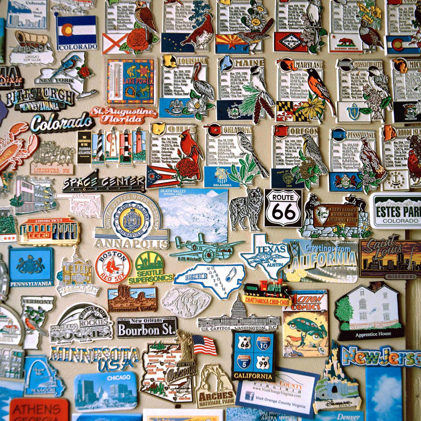 Various state, city, national park, and landmark magnets displayed on a wall.