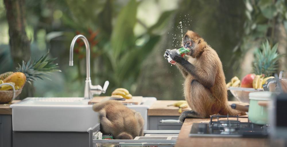 A monkey is sitting on a kitchen counter, eating a slice of pizza.