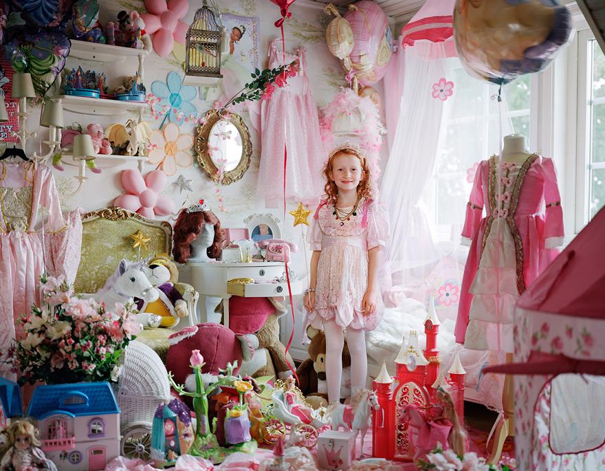 A young girl in a pink dress among toys and pink-themed decor.