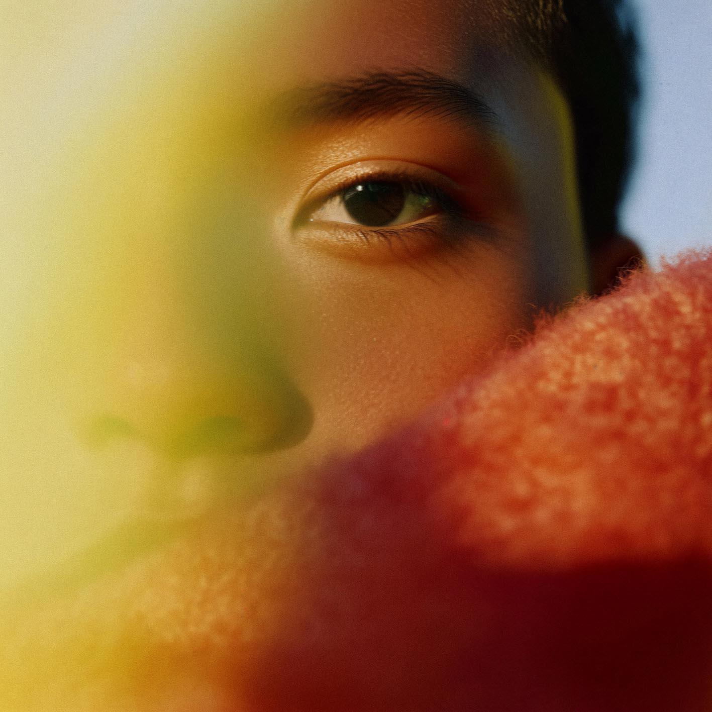 A close-up of a person's eye with a subtle, shimmering effect on the iris, surrounded by a soft, blurred background.