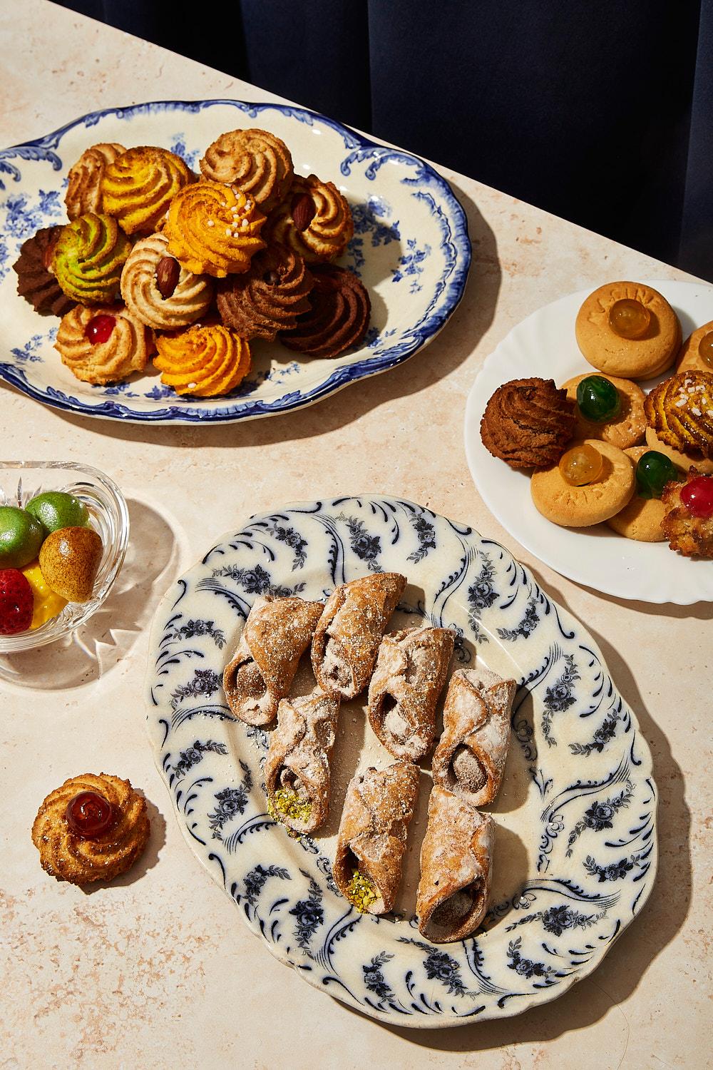 A selection of Italian pastries and sweets, including cannelli, pizzichi, and other traditional Italian desserts, on a table in a studio setting.