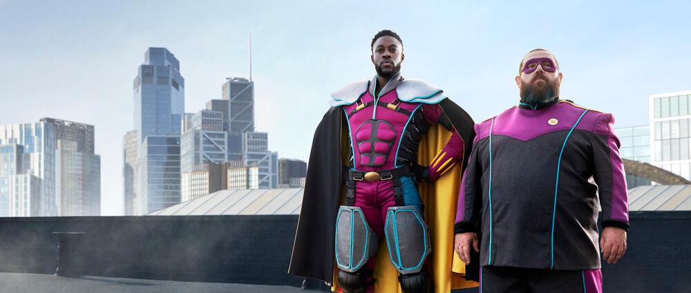 Two men in superhero costumes standing in front of a city skyline.