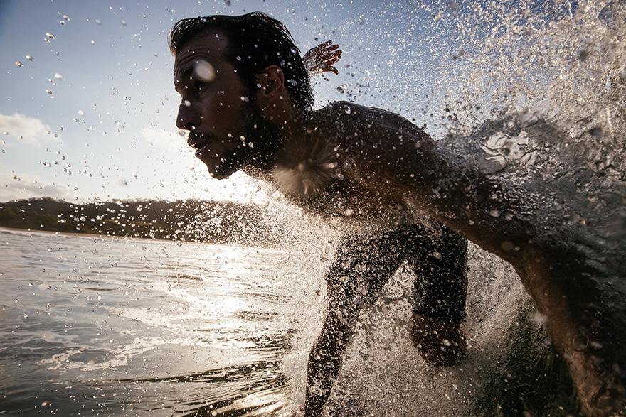 A man surfing in the ocean, wearing a wetsuit.