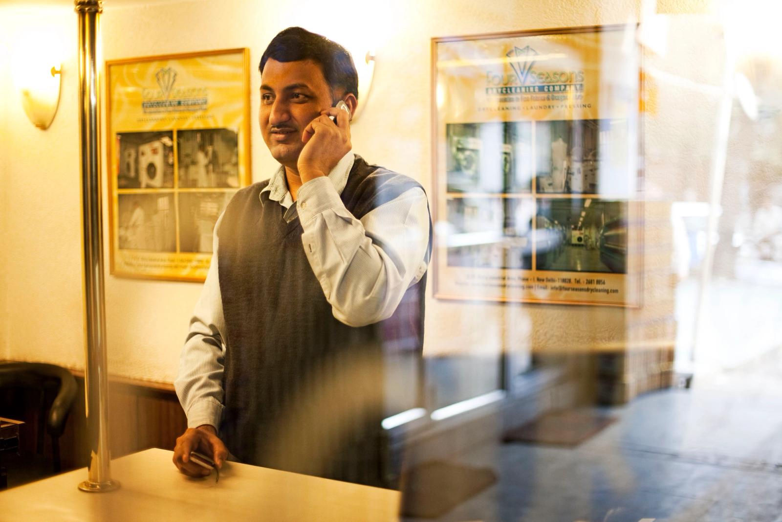 A man stands behind a reception desk, holding a phone.