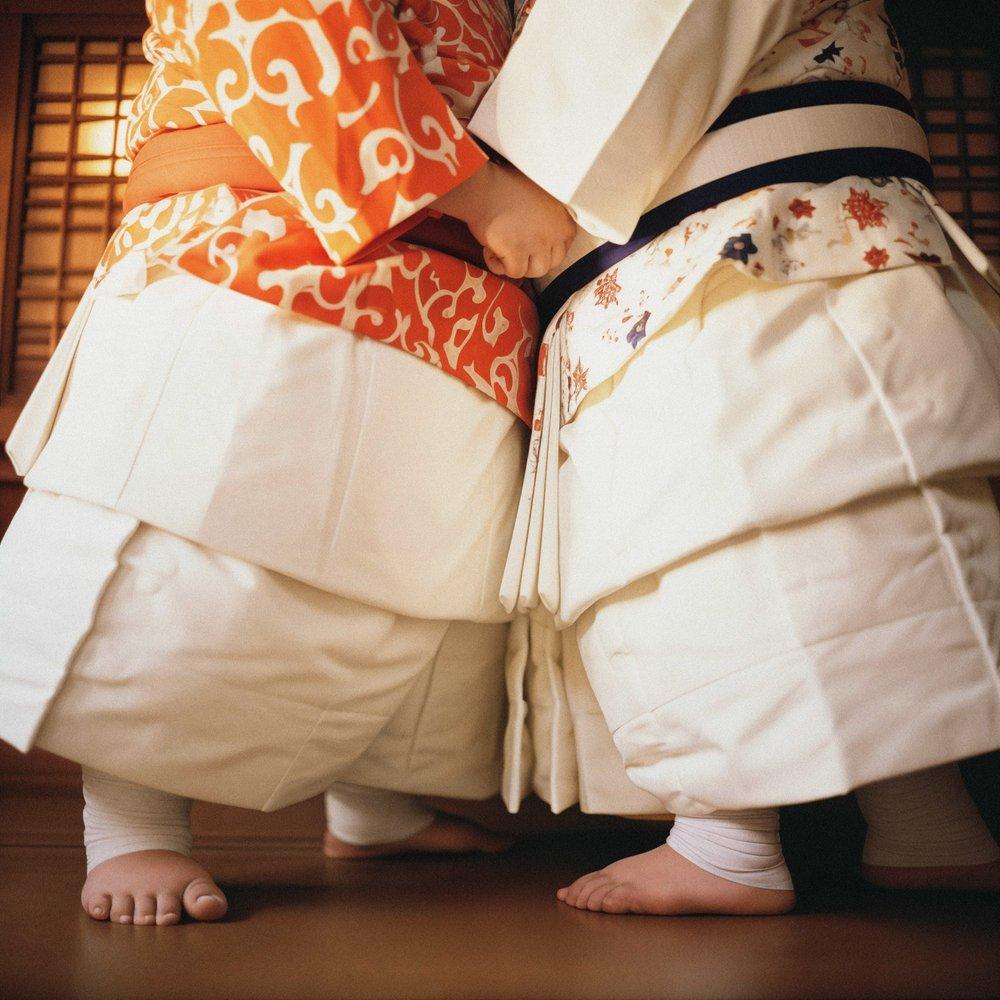 Two women in traditional kimonos stand together in a Japanese-style room with sliding doors.
