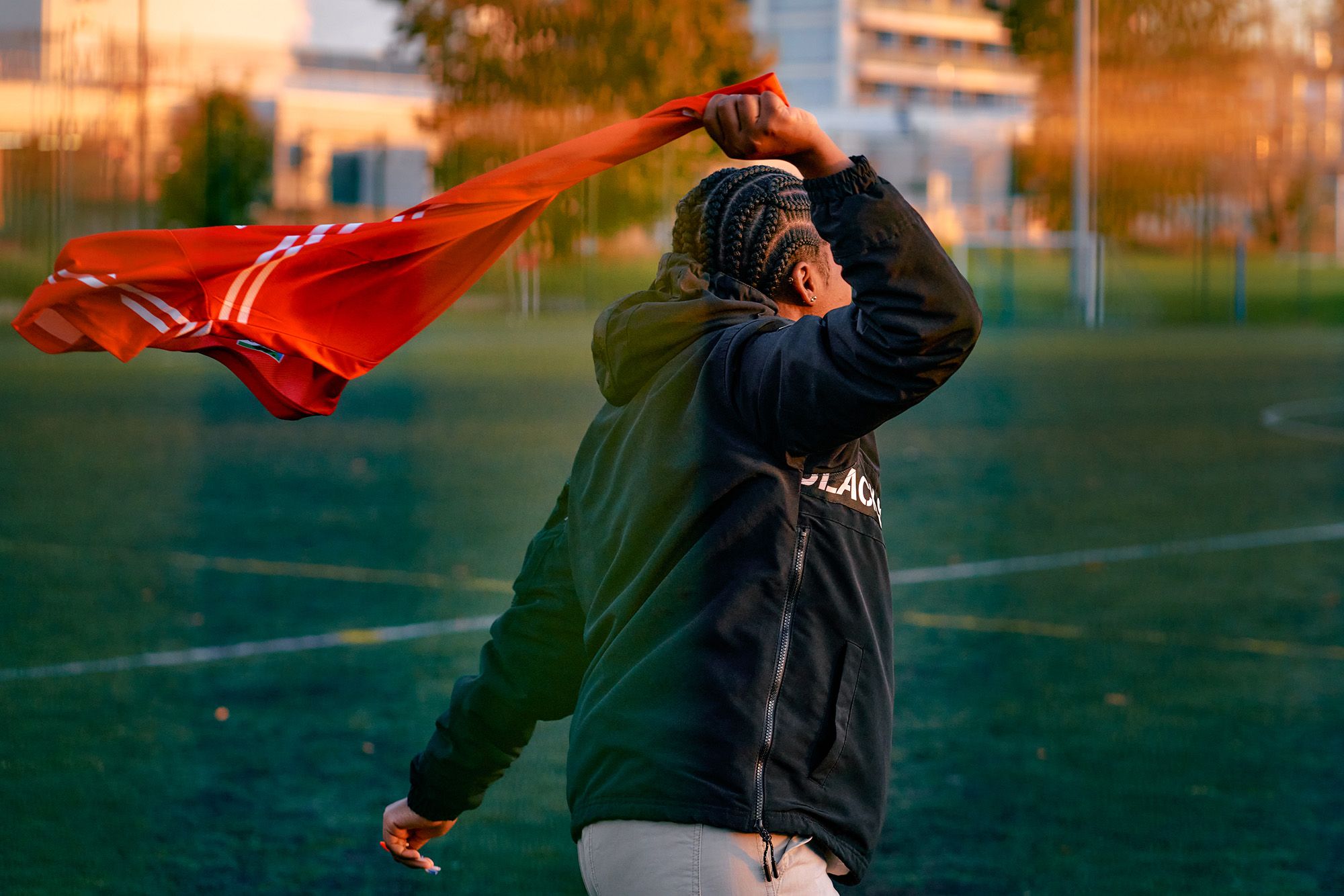 A person holding a red flag, likely a sports referee or flag bearer, in a sports stadium or field.