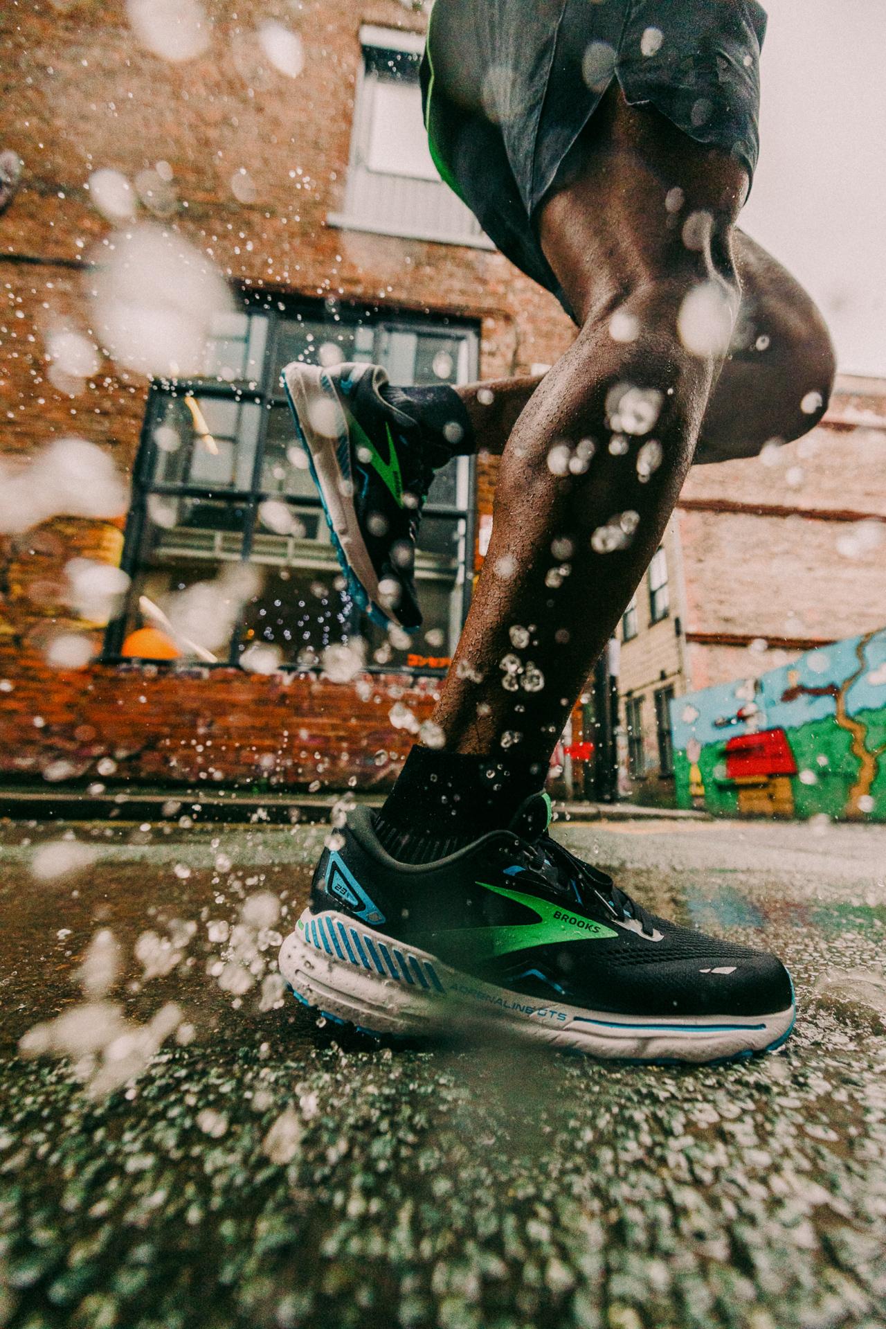 A person running in the rain, wearing a pair of running shoes and a rain jacket.
