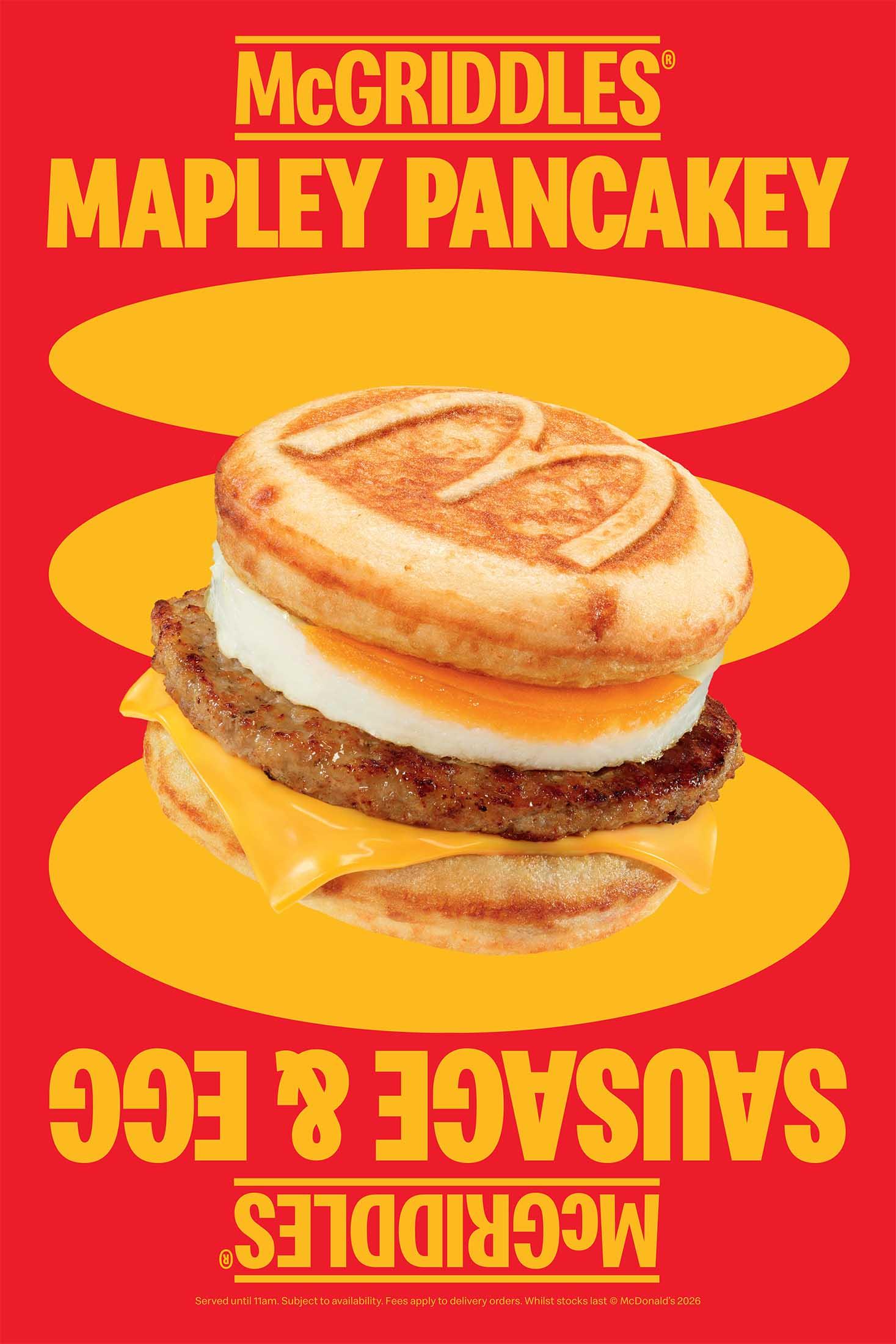 A bright red advertisement featuring a McDonald’s McGriddles breakfast sandwich. The sandwich shows a sausage patty, egg, and melted cheese between two round maple-flavoured griddle cakes stamped with an “M.”