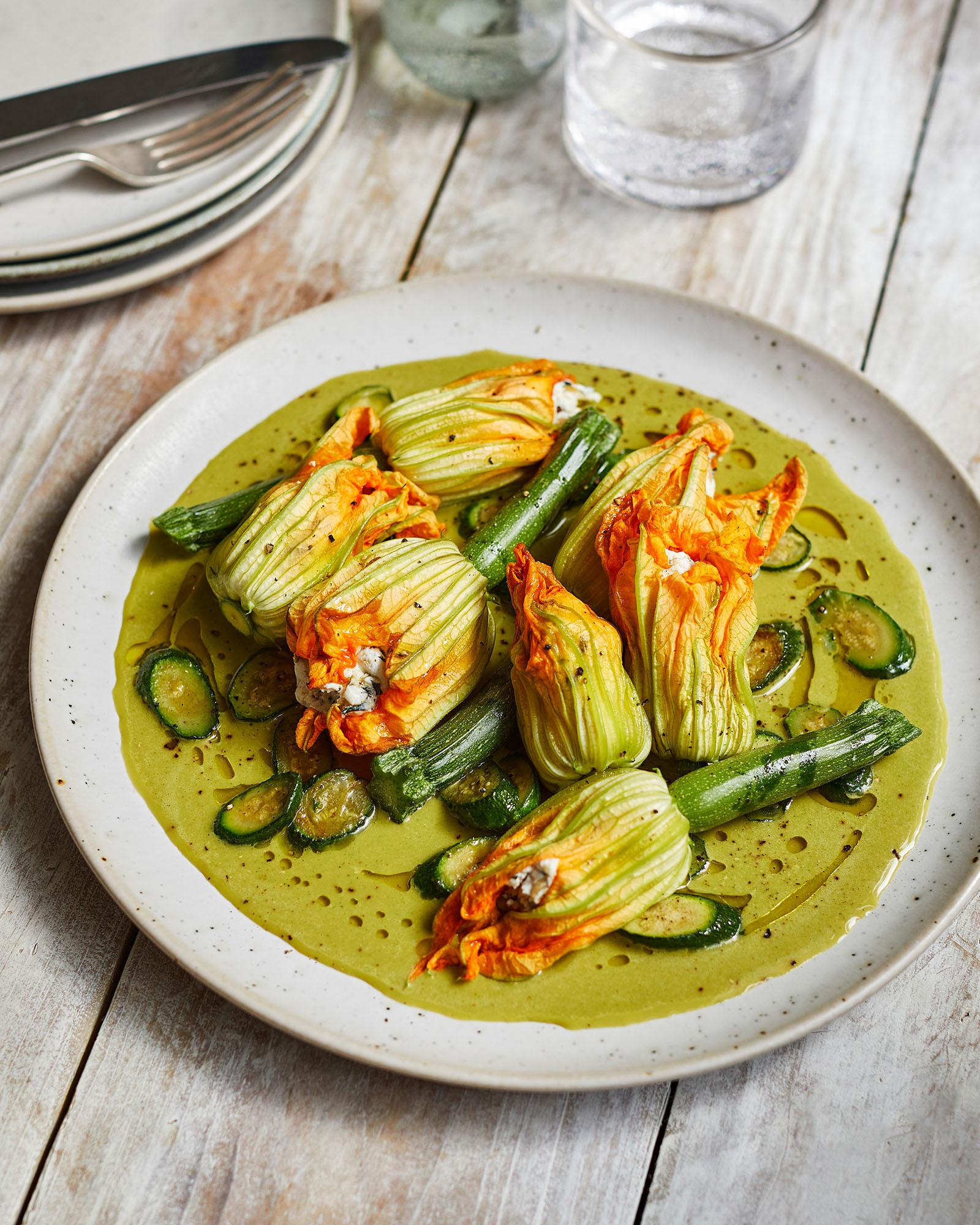 A plate of zucchini flowers and zucchini, likely served as a side dish or appetizer, with a light, possibly olive, sauce.