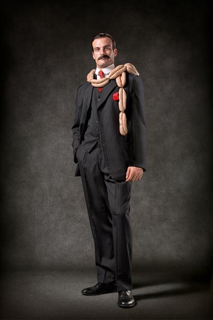 A man in a suit and tie, with a snake wrapped around his neck, in a dark and moody setting.
