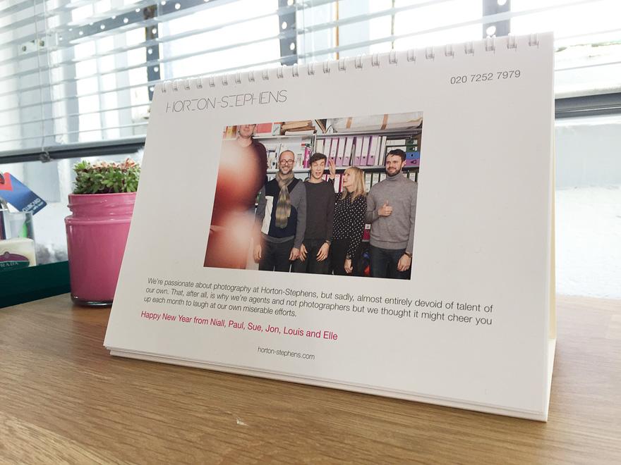A calendar featuring a group of people in a studio, with a photographer in the background.