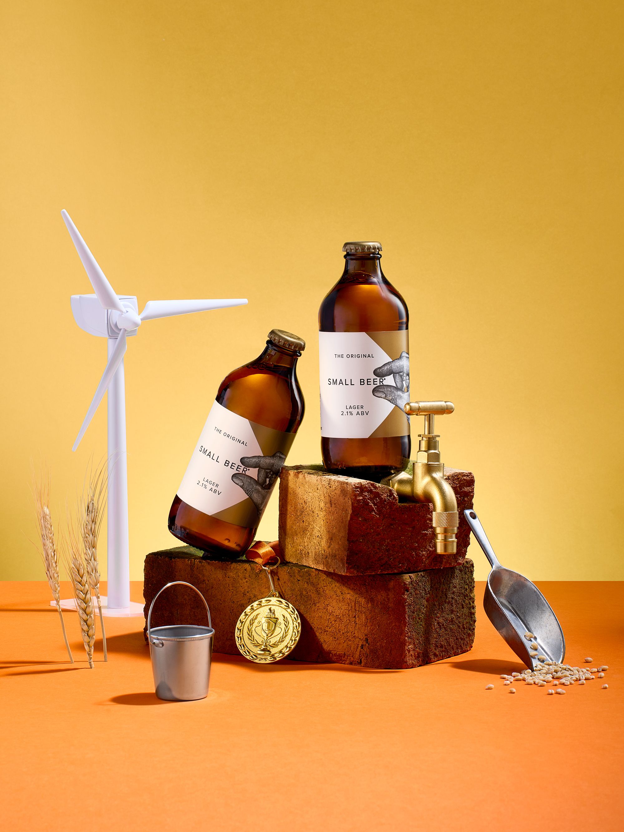 A still life of two bottles of beer, a wind turbine, and various beer-related objects.