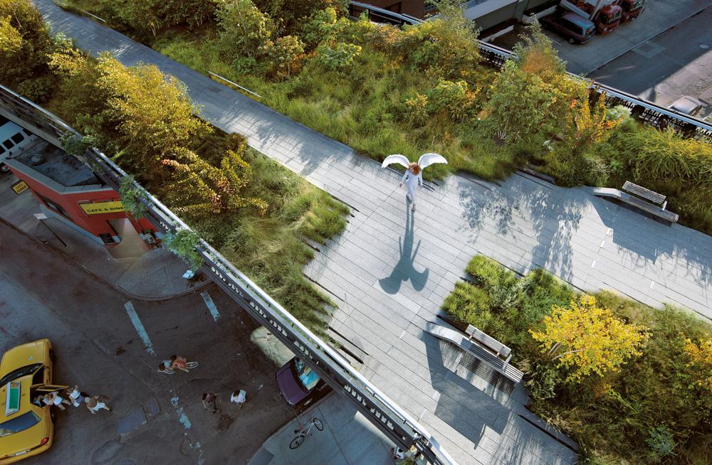 Aerial view of a city street with a person in a white outfit with wings, surrounded by trees and cars.