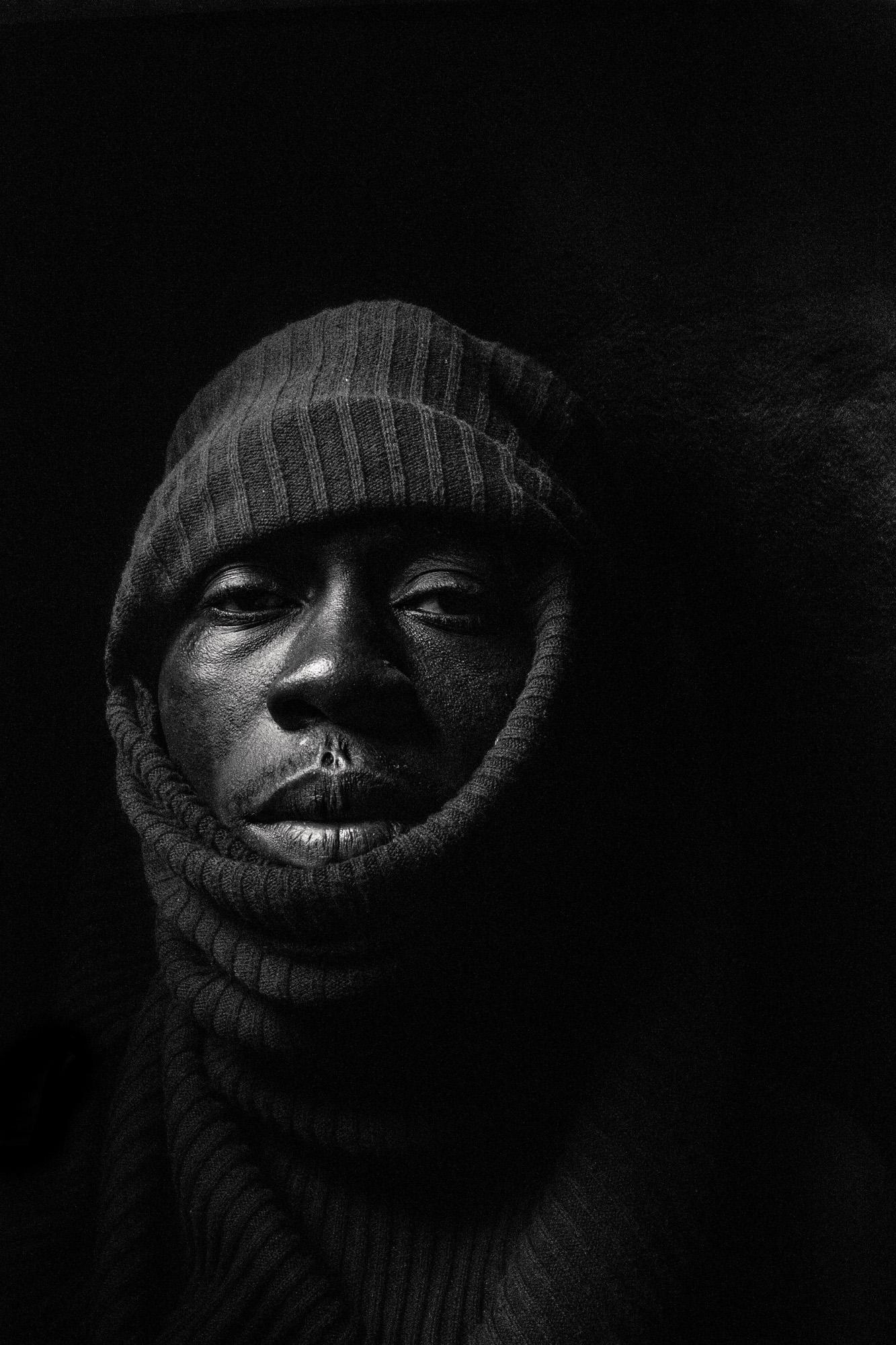 A person wearing a dark, hooded, and face-concealing balaclike garment, likely a ski mask or a similar type of winter clothing.