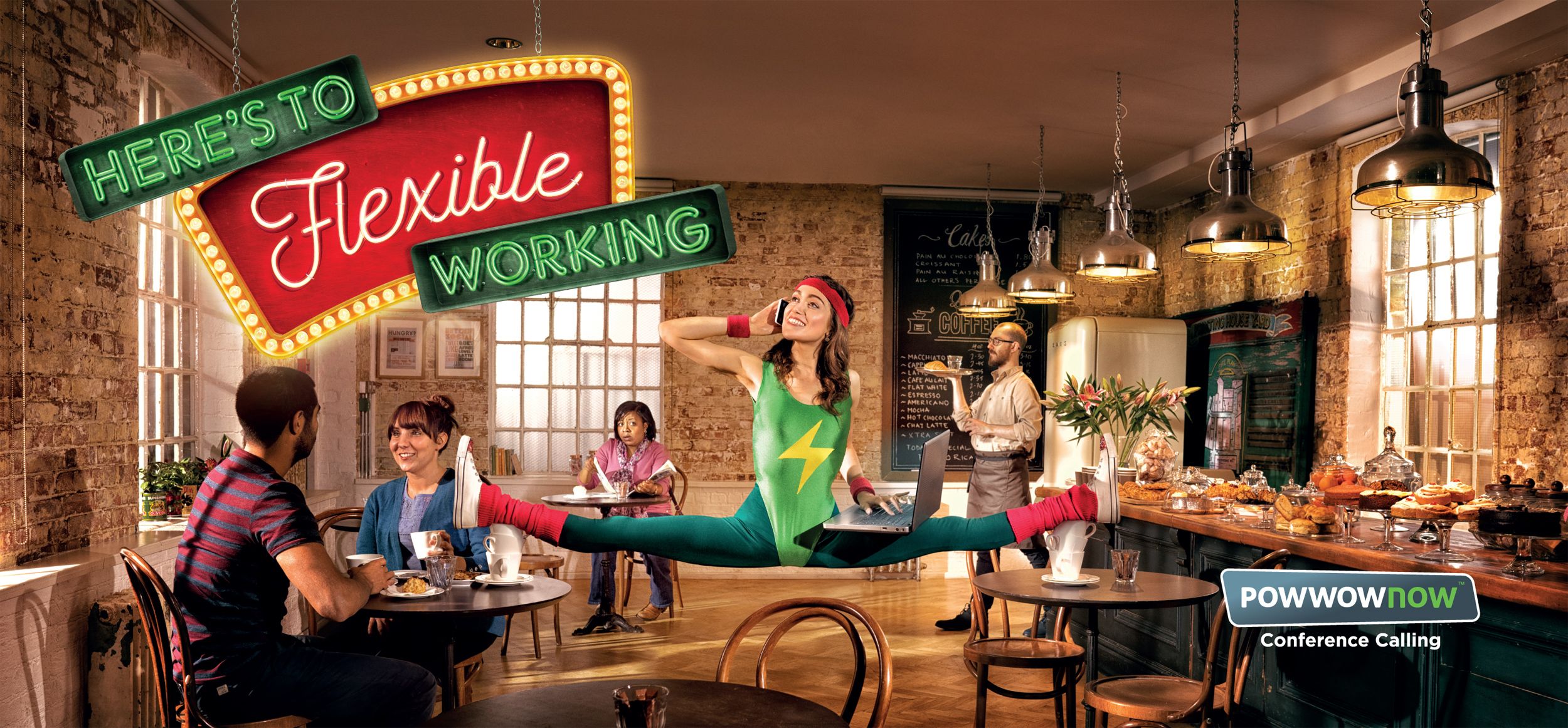 A woman in a green and yellow leotard with a lightning bolt performs a split in a cafe, while others sit at a table.