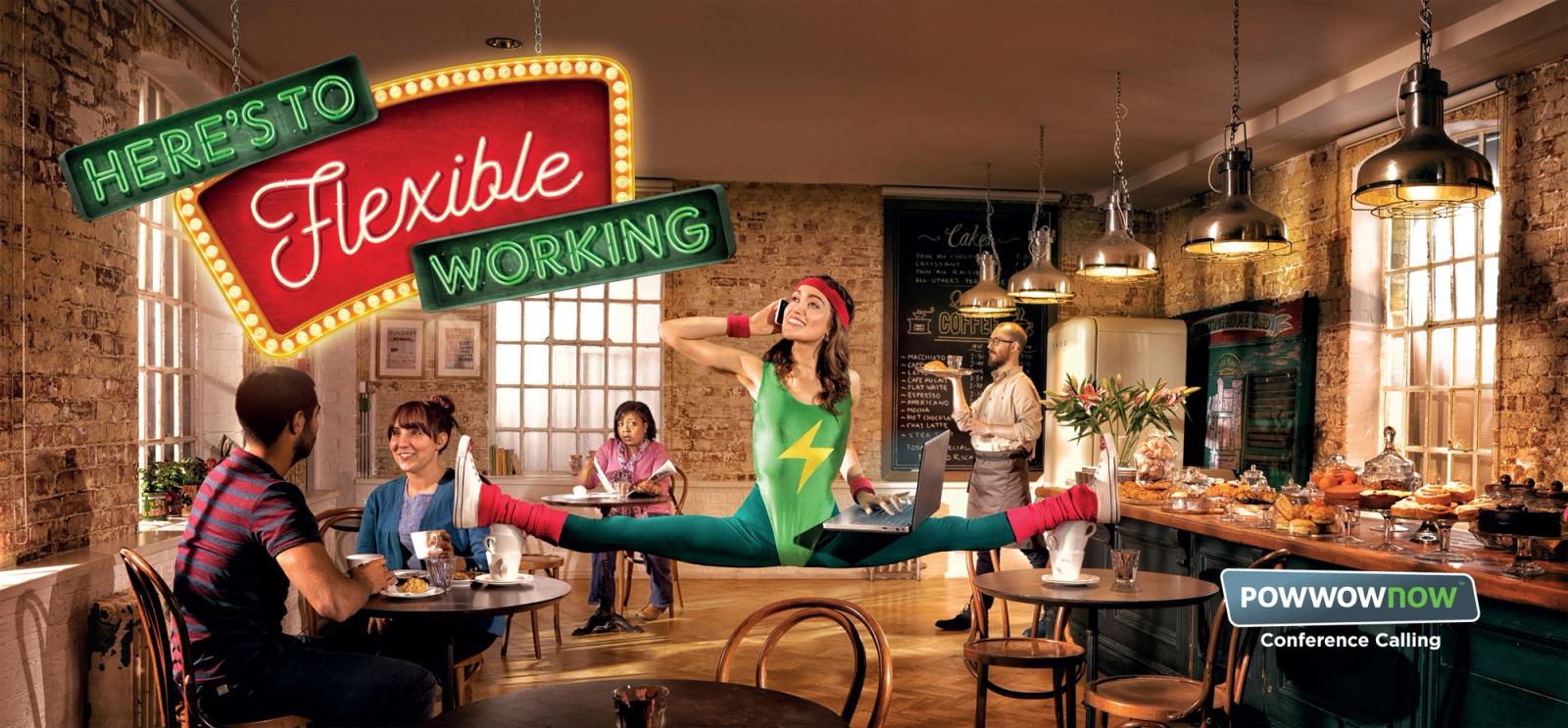 A woman in a green and yellow leotard with a lightning bolt performs a split in a cafe, while others sit at a table.