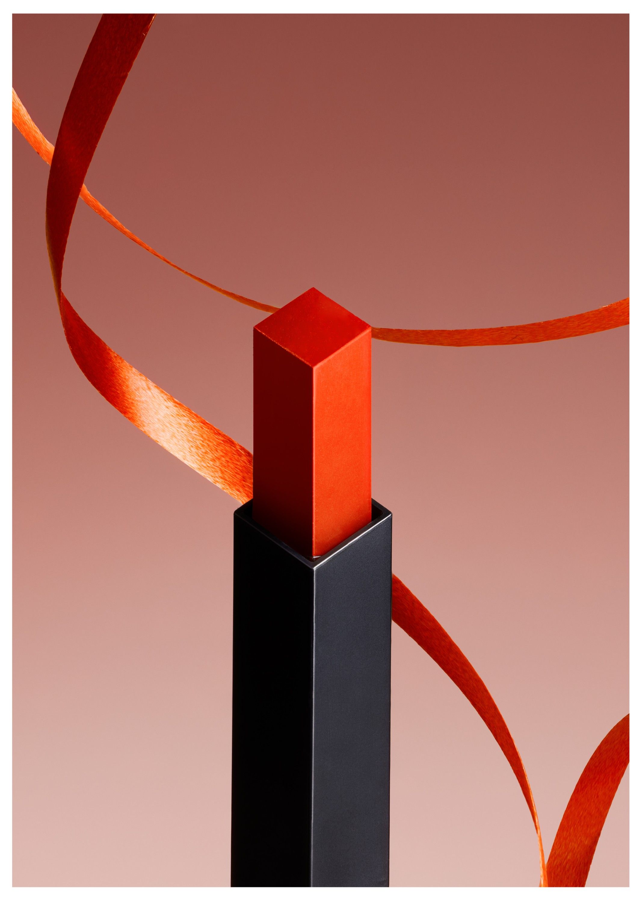 A red lipstick with a black base and a red ribbon wrapped around it.