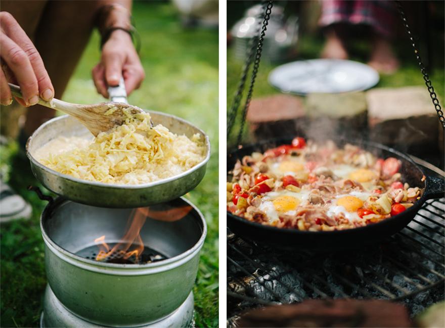 A person is cooking a breakfast skillet with eggs, vegetables, and meat in a cast-iron skillet over a campfire.