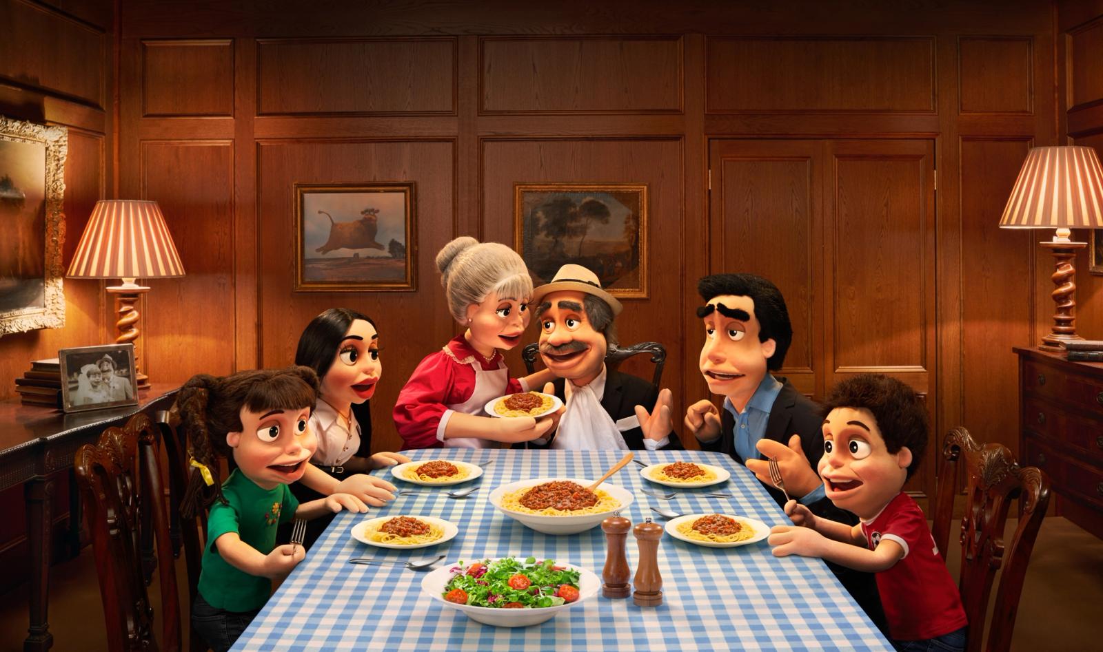 A group of anthropomorphic figures, including a chef, a teacher, a doctor, and a child, sit at a table eating spaghetti and salad.