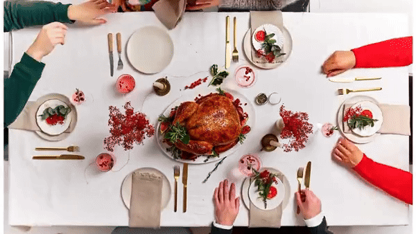 A table set for a festive holiday meal, with a roasted turkey as the centerpiece, surrounded by various dishes and decorations.
