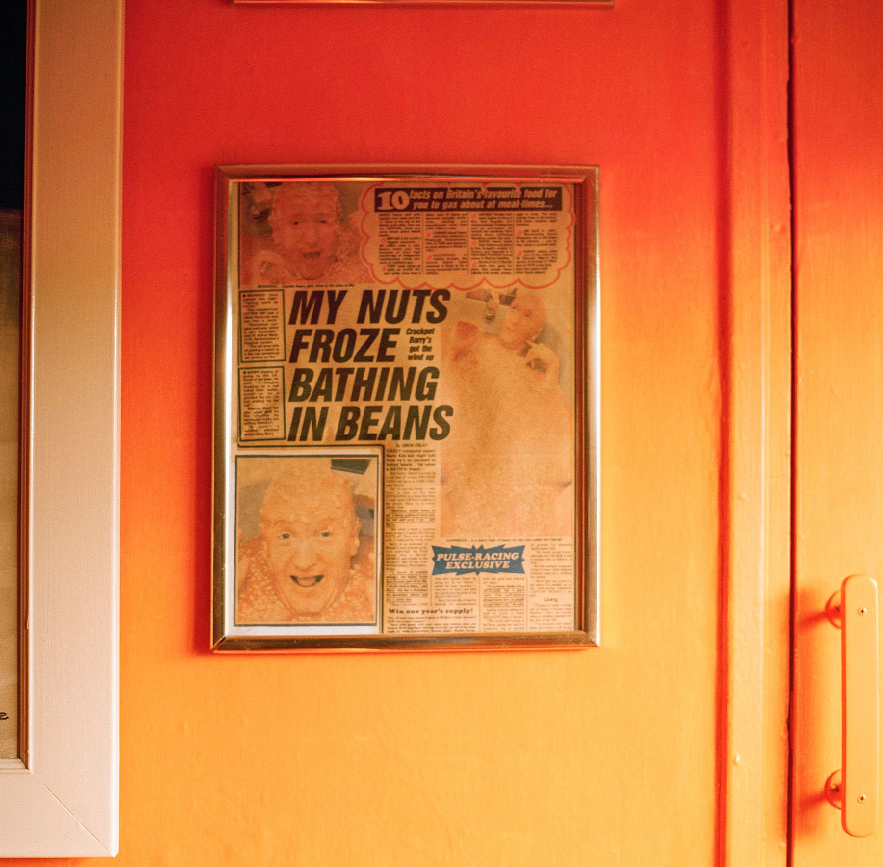A framed newspaper clipping on the wall with the headline 'My Nuts Froze, Bathing in Beans'.