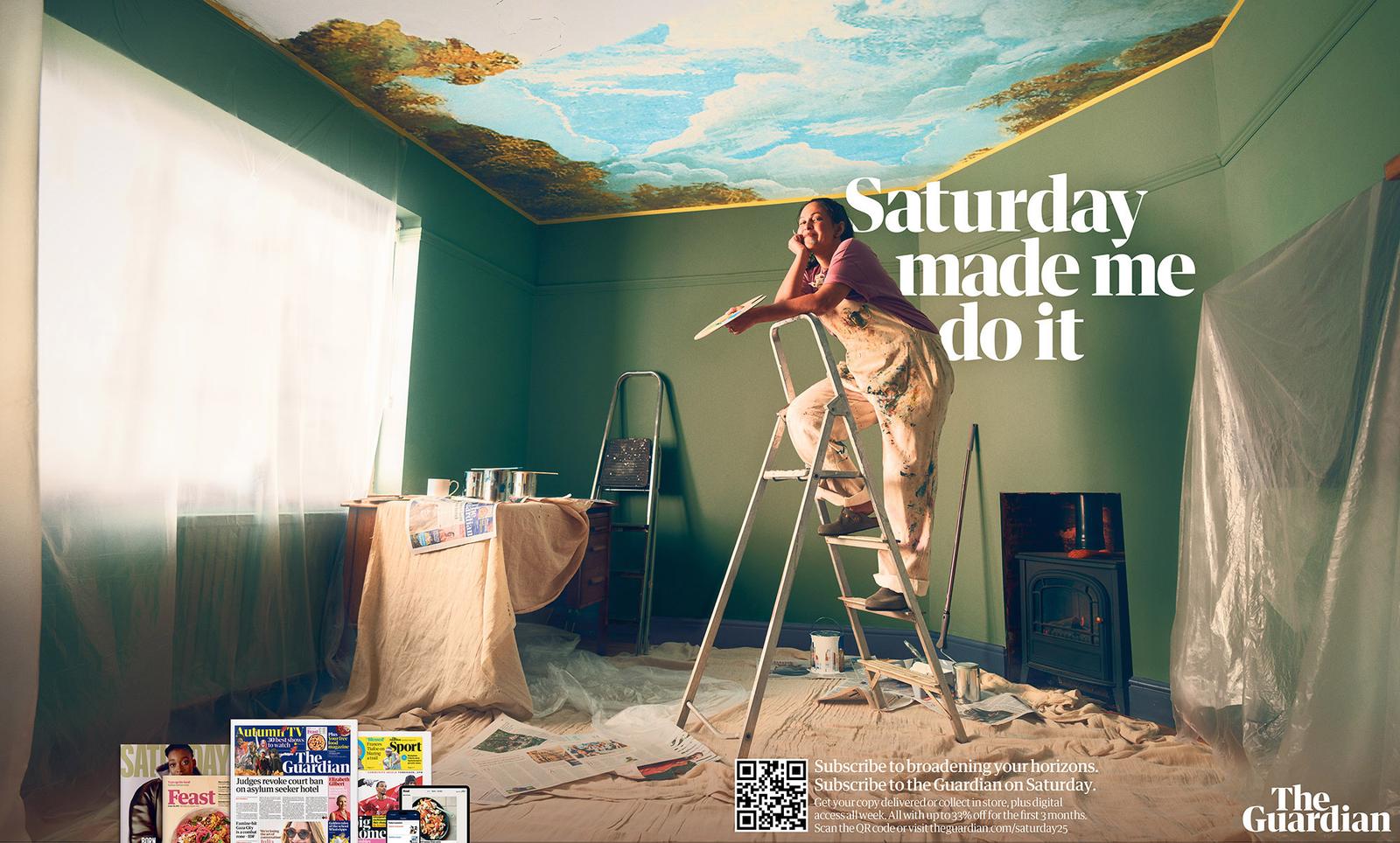 A woman in a pink t-shirt and floral overalls is painting a ceiling with a sky and clouds design, while standing on a ladder in a room with a table, a magazine, and a newspaper.