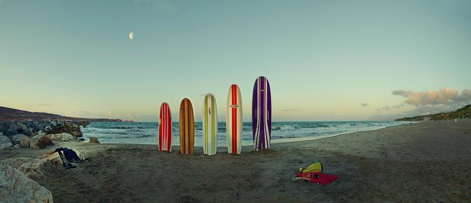 A beach with surfboards and beach chairs, with a few people in the distance.