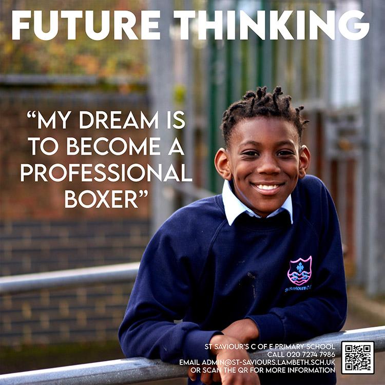 A young boy in a school uniform is leaning on a metal railing, smiling at the camera.